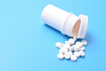 Pills spilling out of pill bottle and isolated on blue background. Top view with copy space. Medicine concept