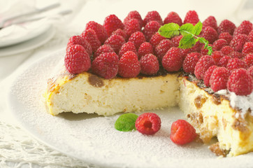 Cheesecake, souffle, cream mousse, pudding dessert with fresh raspberries and mint leaves on a white plate