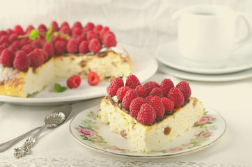 Cheesecake, souffle, cream mousse, pudding dessert with fresh raspberries and mint leaves on a white plate