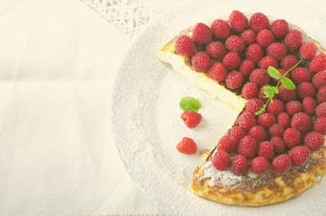 Cheesecake, souffle, cream mousse, pudding dessert with fresh raspberries and mint leaves on a white plate