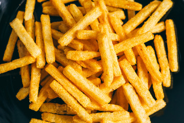Corn snacks are on the black plate. Yellow texture