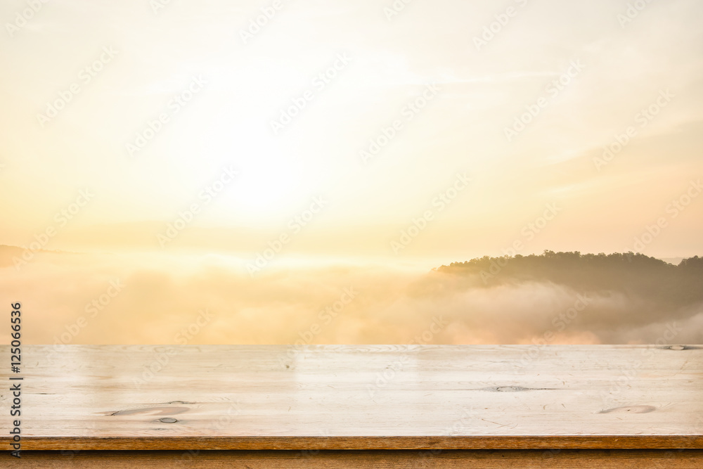 Poster empty top of wooden table over sea of mist over blurred mountain background. for display of your pro