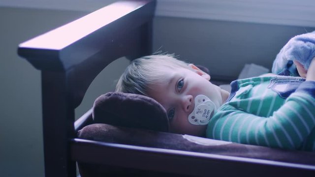 Adorable baby boy laying on a changing table with a pacifier in his mouth, looking up
