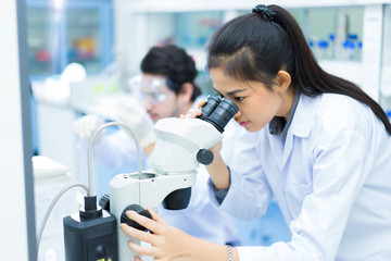 group of scientists working at the laboratory .she use microscop
