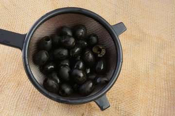 Rinsed Canned pitted black olives in strainer in bowl