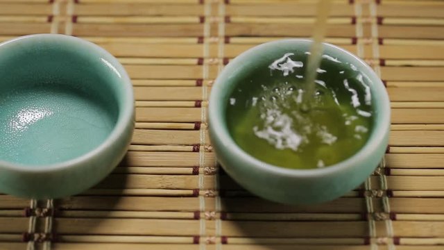 Green tea pouring into asian cup