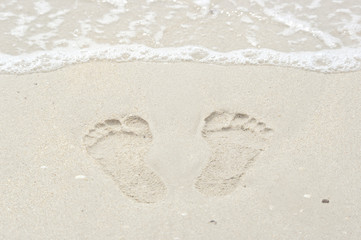 Footprint in the sand and small wave