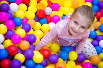 Fototapeta na wymiar Girl in the playing room with many colored balls
