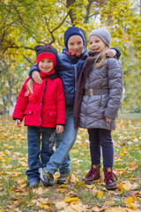 Three kids embracing among autumn