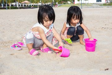 Asian Chinese little sister playing sand at beach