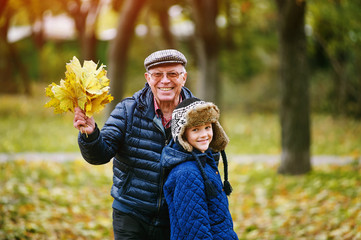 Grandfather walking with grandson playing in autumn Park