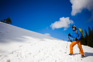 Mountain climber walks on a snowy slope.