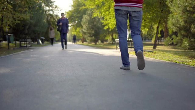 A woman in jeans walking in the park. Asphalt.