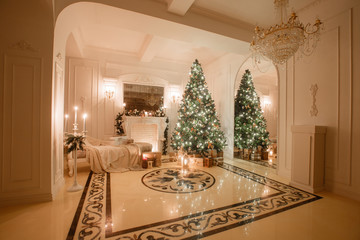 Christmas evening by candlelight. classic apartments with a white fireplace, decorated tree, bright sofa, large windows