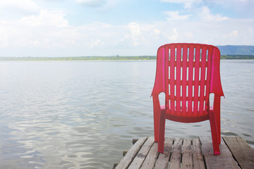 Fototapeta na wymiar red chair on wooden bridge near sea beach