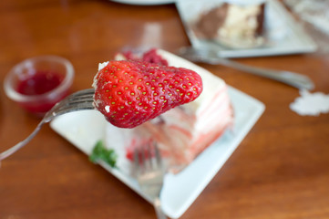 Strawberry on a fork,Crepe cake with strawberry sauce on table.selective focus