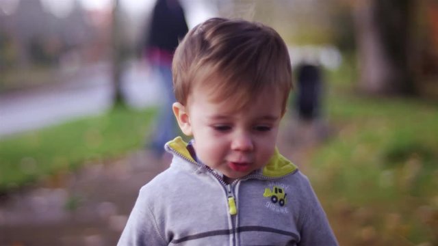 Adorable little boy walking toward the camera in a park on a fall day