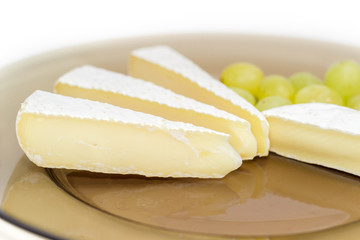 Slices of soft cheese with berries of white table grapes