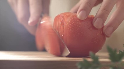 Female hands cutting tomato with knife