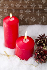 lit candles Christmas decoration with pinecones on snow