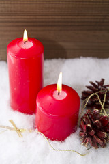 lit candles Christmas decoration with pinecones on snow