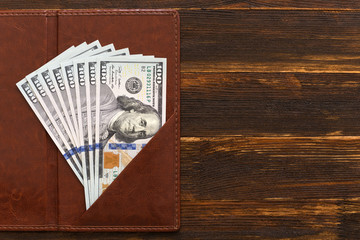 fanned out hundred dollar bills folded in wallet..