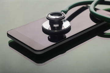 Stethoscope with smart phone on glass table. Medical concept.