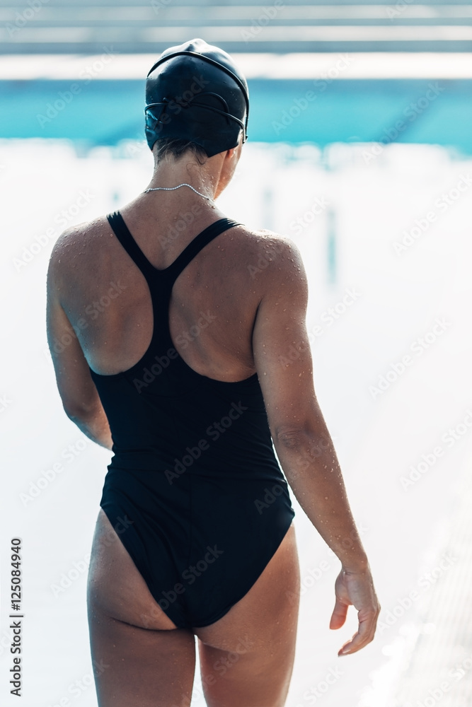 Wall mural Swimmer. Female swimmer walking by the pool