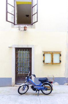 Traditional old Krk town architecture. View of door and open window and old tomos retro automatic motorcycle parked outside at the medieval ancient capital centre.