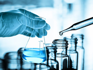 Flask in scientist hand with test tubes in laboratory 
