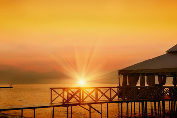 pergola veranda on stilts on the beach at dawn, sunset.  Beautiful sky and the sun rising from the horizon. Natural marine species.
secluded place to relax
