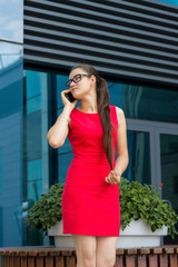 Fototapeta premium woman in red dress using her phone on the street
