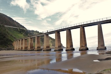 a heavy concrete train bridge crossing a river