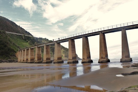 a heavy concrete train bridge crossing a river