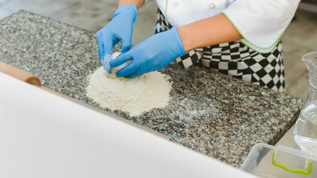 Closeup hand of chef baker in white uniform making pizza