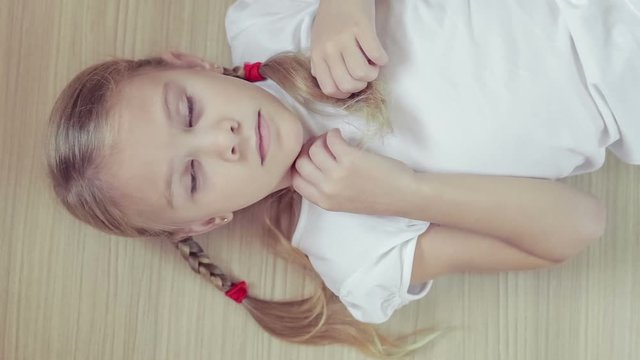 Portrait sad little girl lying on floor at home 