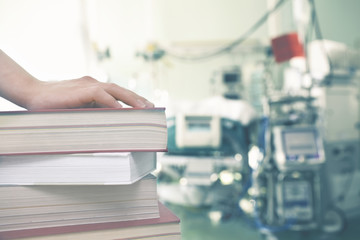 Hand on the books against the background of medical equipment