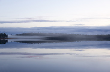Magical view. Foggy landscape at the lake during night time in Finland