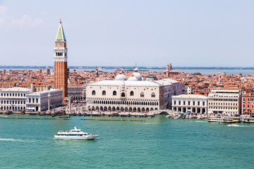 Fototapeta premium Aerial view of a boat sailing in front of the famous San Marco Campanile and the Doges Palace on the Grand Canal in Venice, Italy.