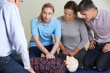Woman Demonstrating CPR On Training Dummy In First Aid Class