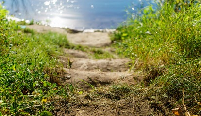Stairs from the ground, descent to the river. Sunny day, blurred background