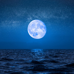 Naklejka na ściany i meble Full moon rising over empty ocean at night