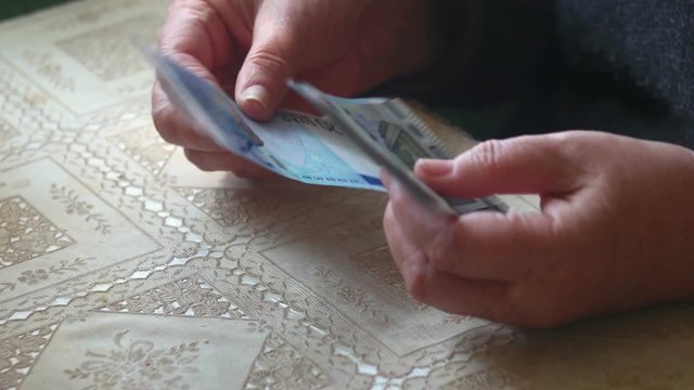 Aged lady counting euro paper money