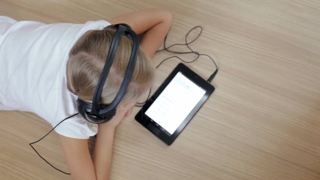 Little girl on the floor in the room using tablet 