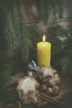 Light candle and Christmas cookies with Christmas and New Years decor and Christmas tree on dark wooden background