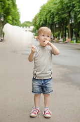 Small baby boy is eating cotton candy