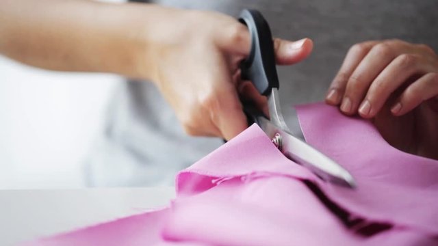 woman with tailor scissors cutting out fabric