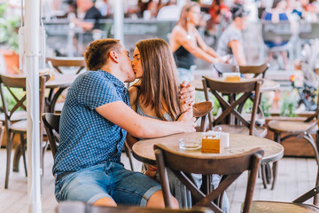 young couple in an open-air cafe. Man kiss woman. Outdoor restaurant terace.