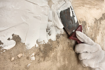hand in glove plastering concrete wall with spatula
