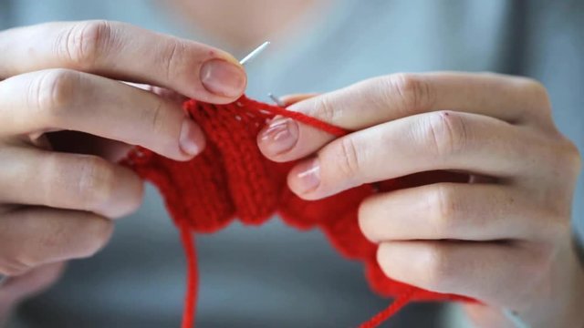 woman knitting with needles and red yarn